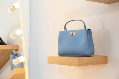 Photo of Stylish woman's bag on shelf in boutique