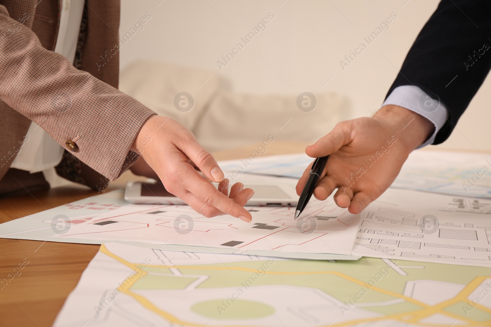 Photo of Professional cartographers working with cadastral map at table in office, closeup