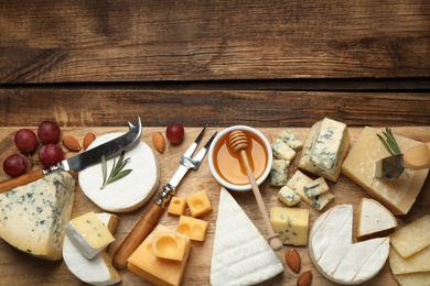 Flat lay composition with different sorts of cheese and knives on wooden table