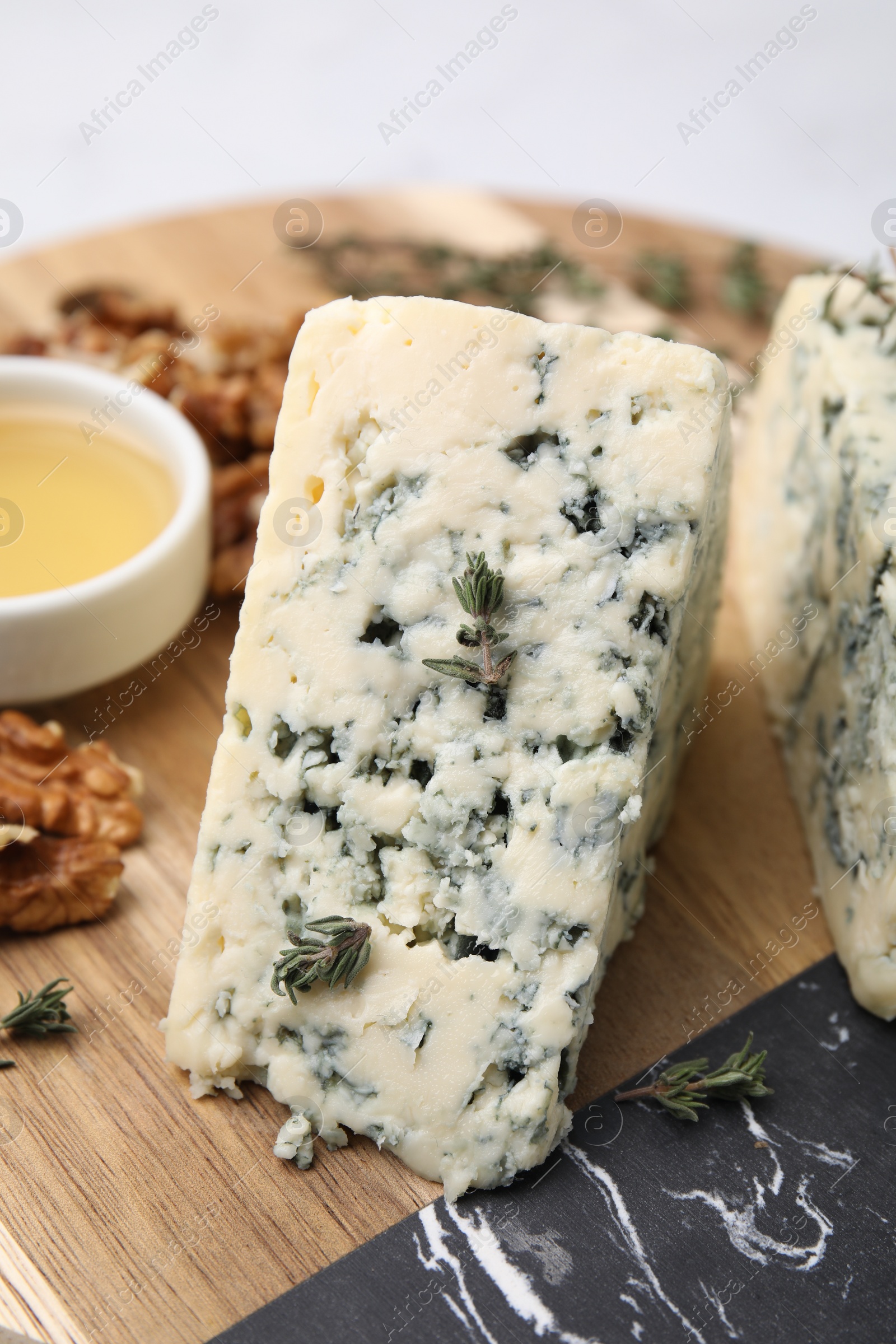 Photo of Tasty blue cheese with thyme, honey and walnuts on wooden board, closeup