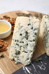 Photo of Tasty blue cheese with thyme, honey and walnuts on wooden board, closeup