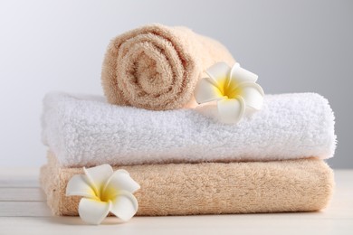 Photo of Closeup viewsoft folded towels and plumeria flowers on white wooden table