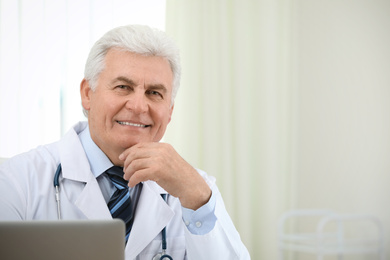 Portrait of senior doctor in white coat at workplace
