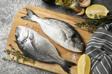 Flat lay composition with raw dorada fish on grey table