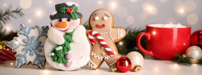 Tasty Christmas cookies and decor on white table against blurred festive lights. Horizontal banner design