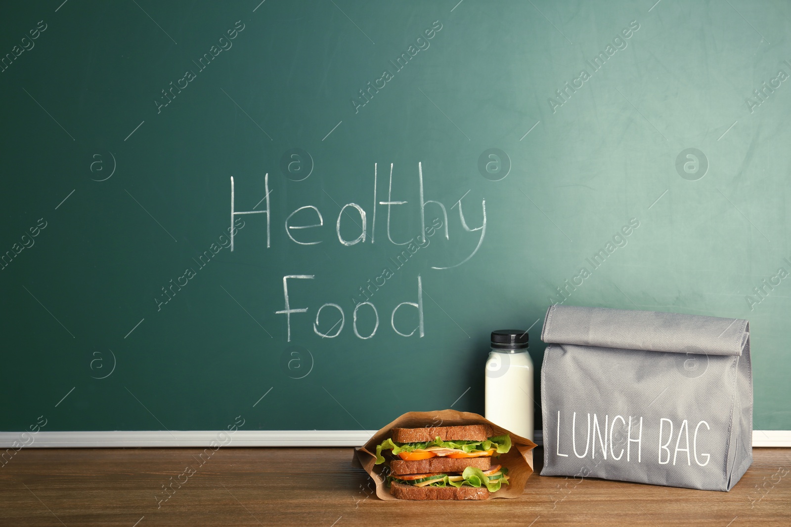 Photo of Lunch for school child on table near chalkboard with written Healthy Food