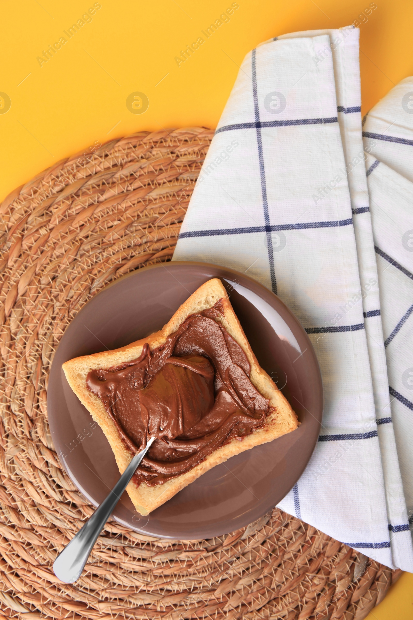 Photo of Tasty toast with chocolate paste on yellow background, top view