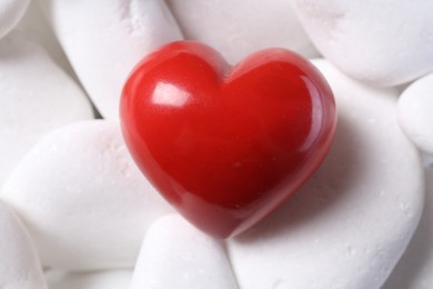 Photo of Decorative heart on white pebble stones, top view