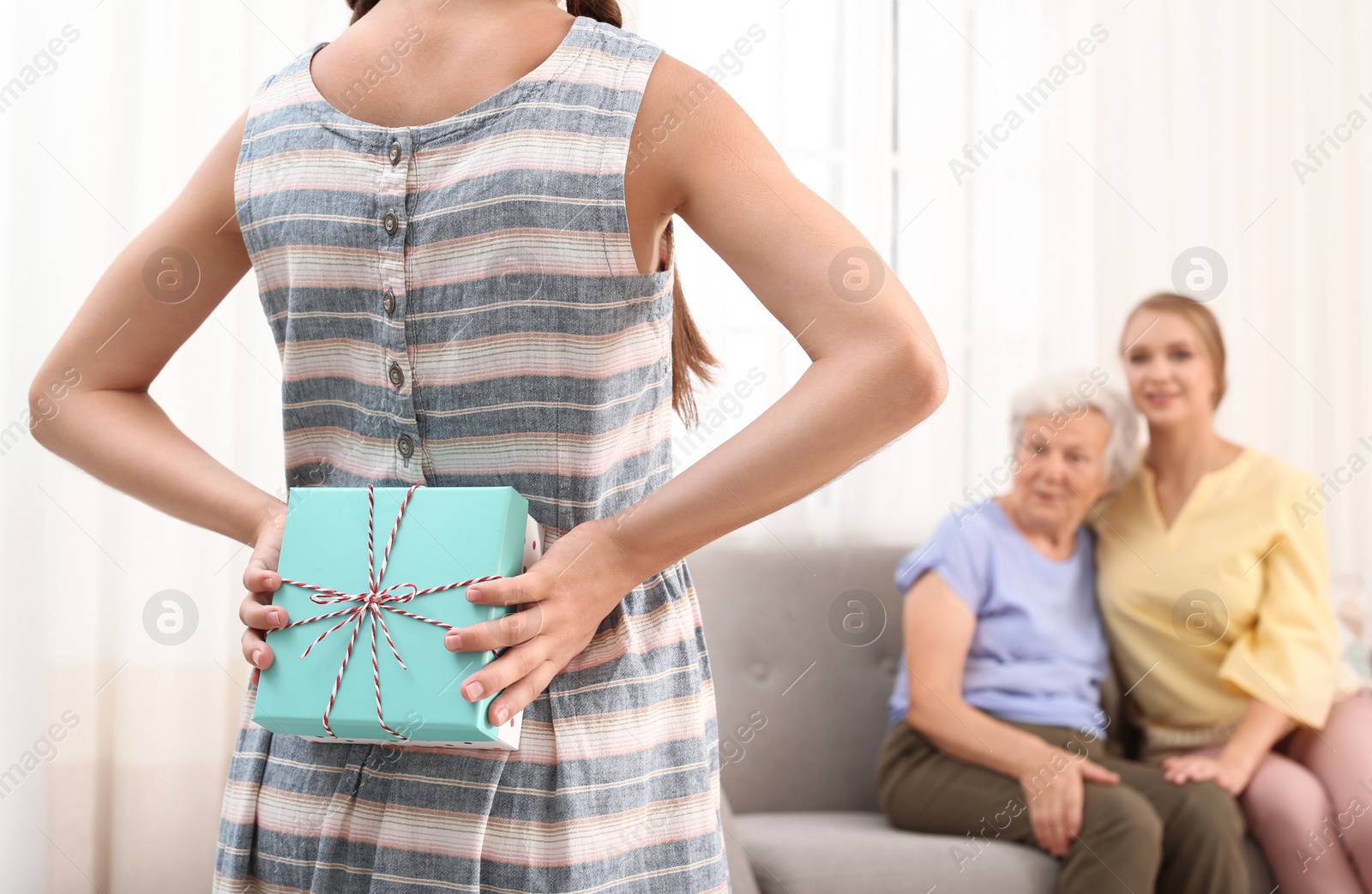 Photo of Girl congratulating her mom and grandmother in living room, closeup