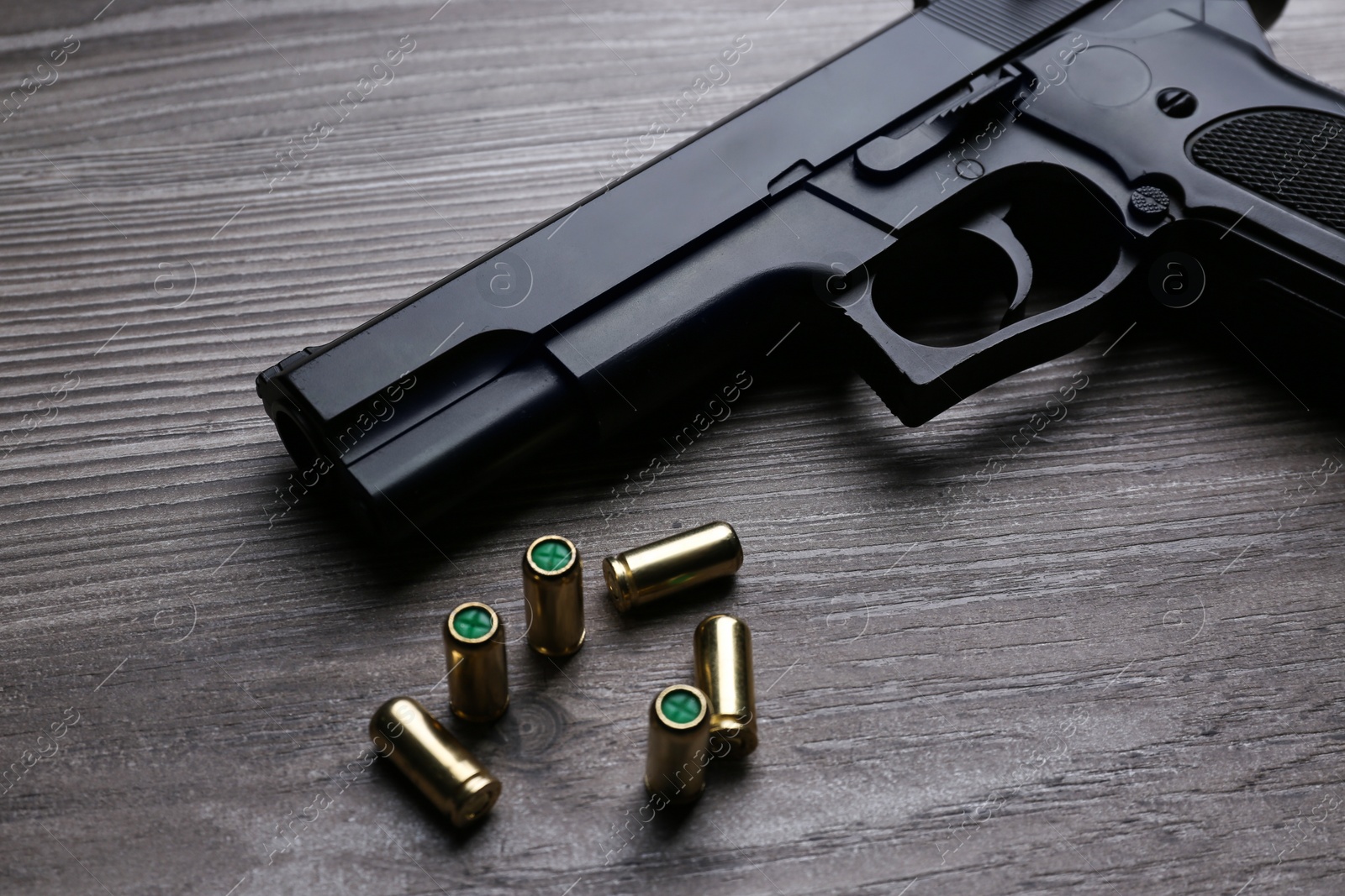 Photo of Pistol and bullets on wooden table. Professional gun