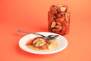 Photo of Different tasty nuts with honey on orange background