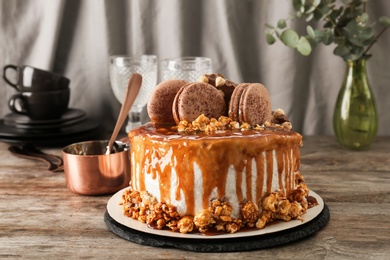 Delicious homemade cake with caramel sauce and popcorn on table