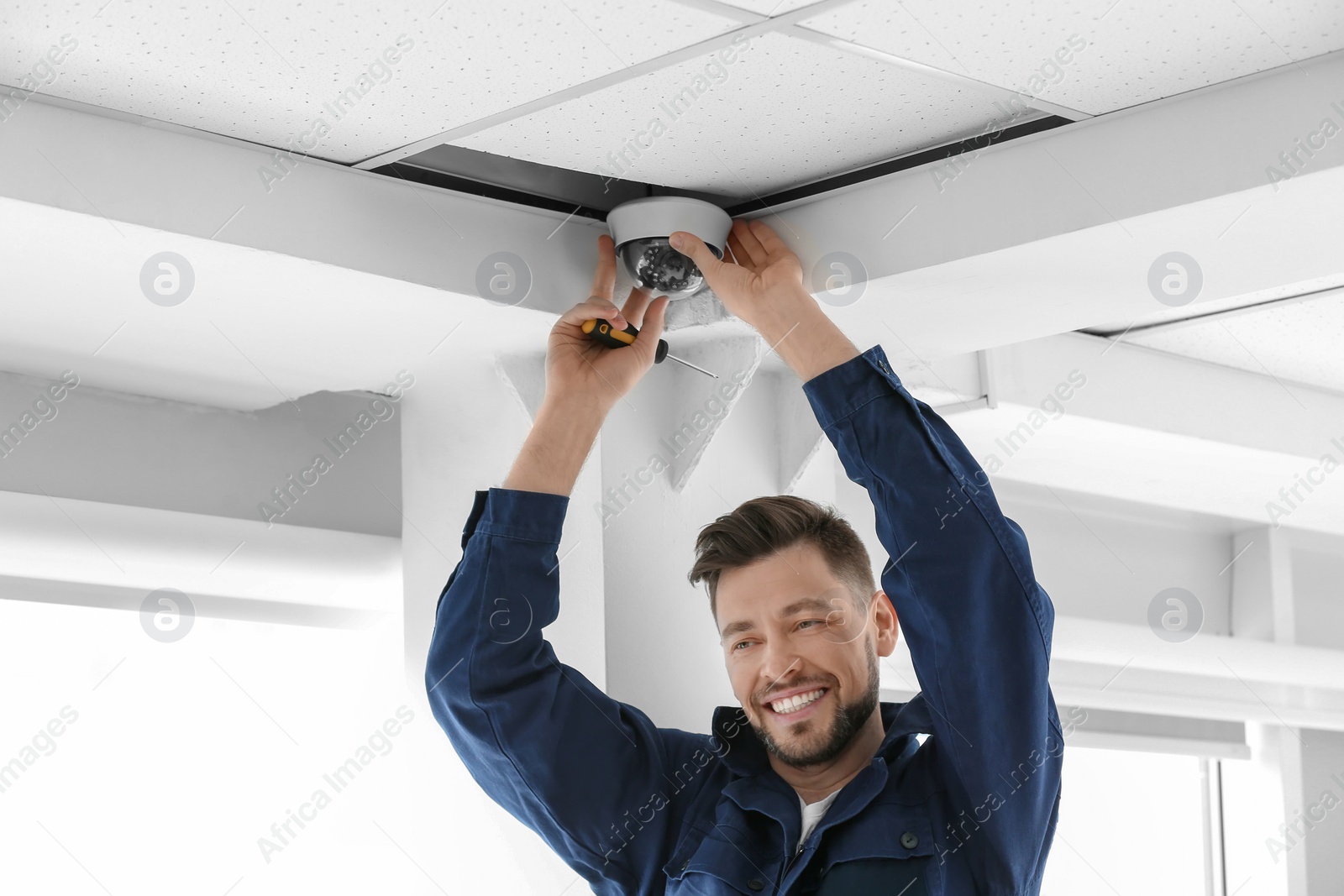 Photo of Technician installing CCTV camera on ceiling indoors