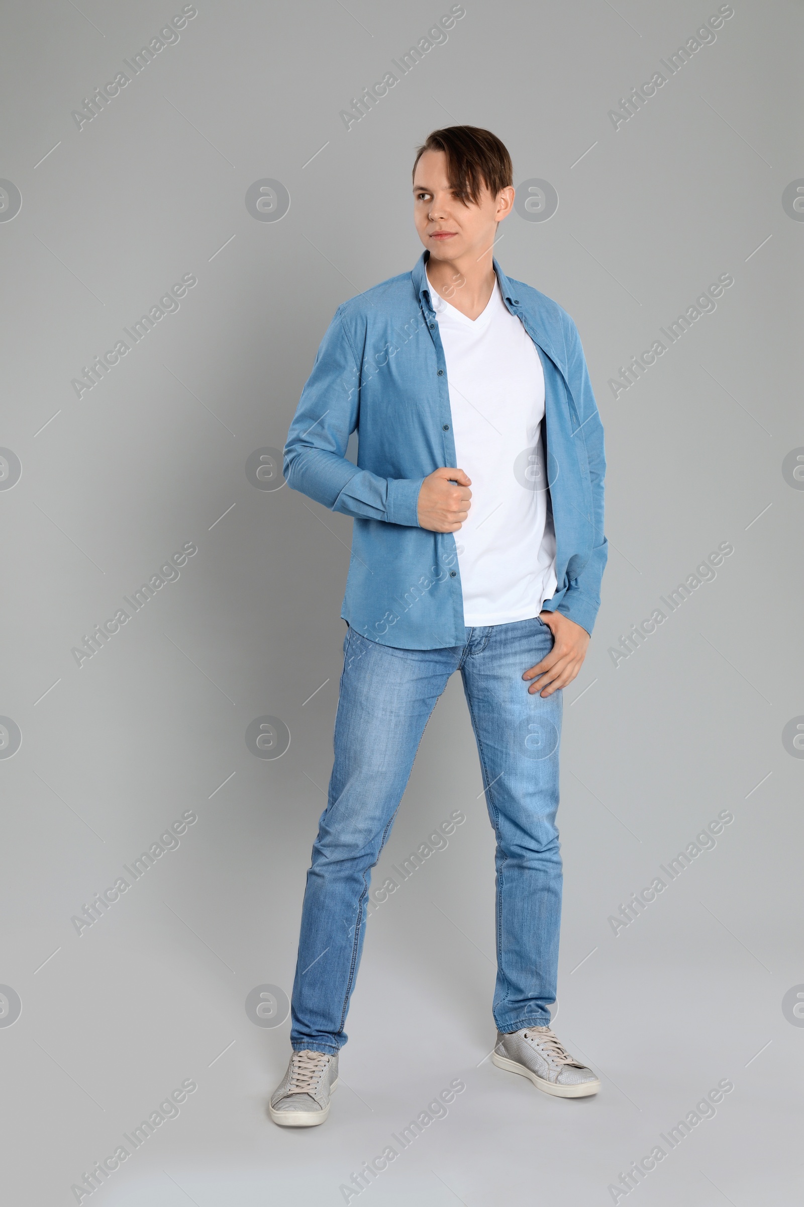 Photo of Young man in stylish jeans on grey background