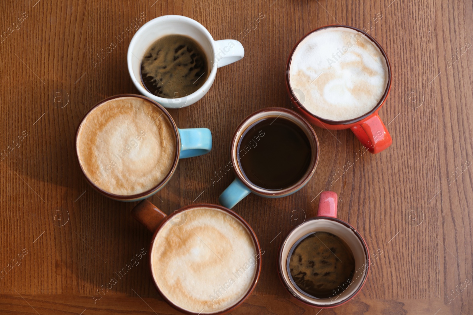 Photo of Cups of fresh aromatic coffee on wooden table, top view