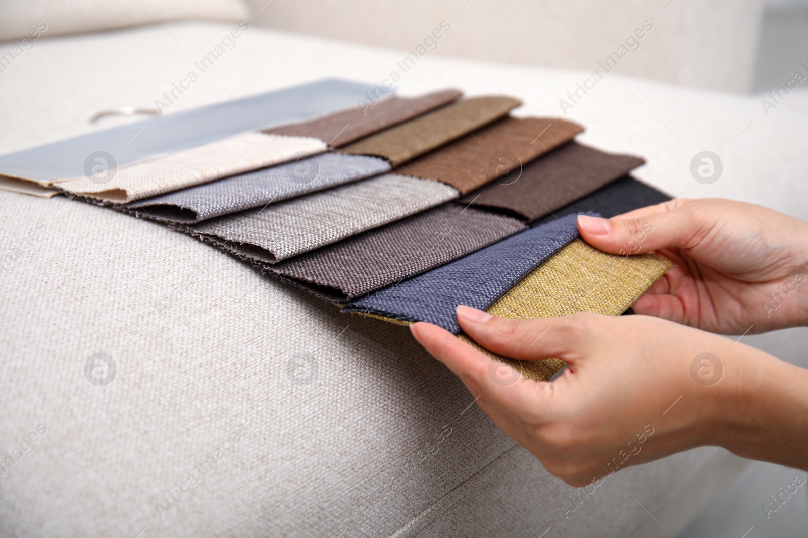 Photo of Woman choosing fabric among colorful samples on beige sofa, closeup