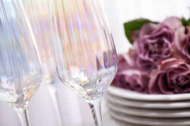 Set of glasses and dishes with flowers on light background, closeup