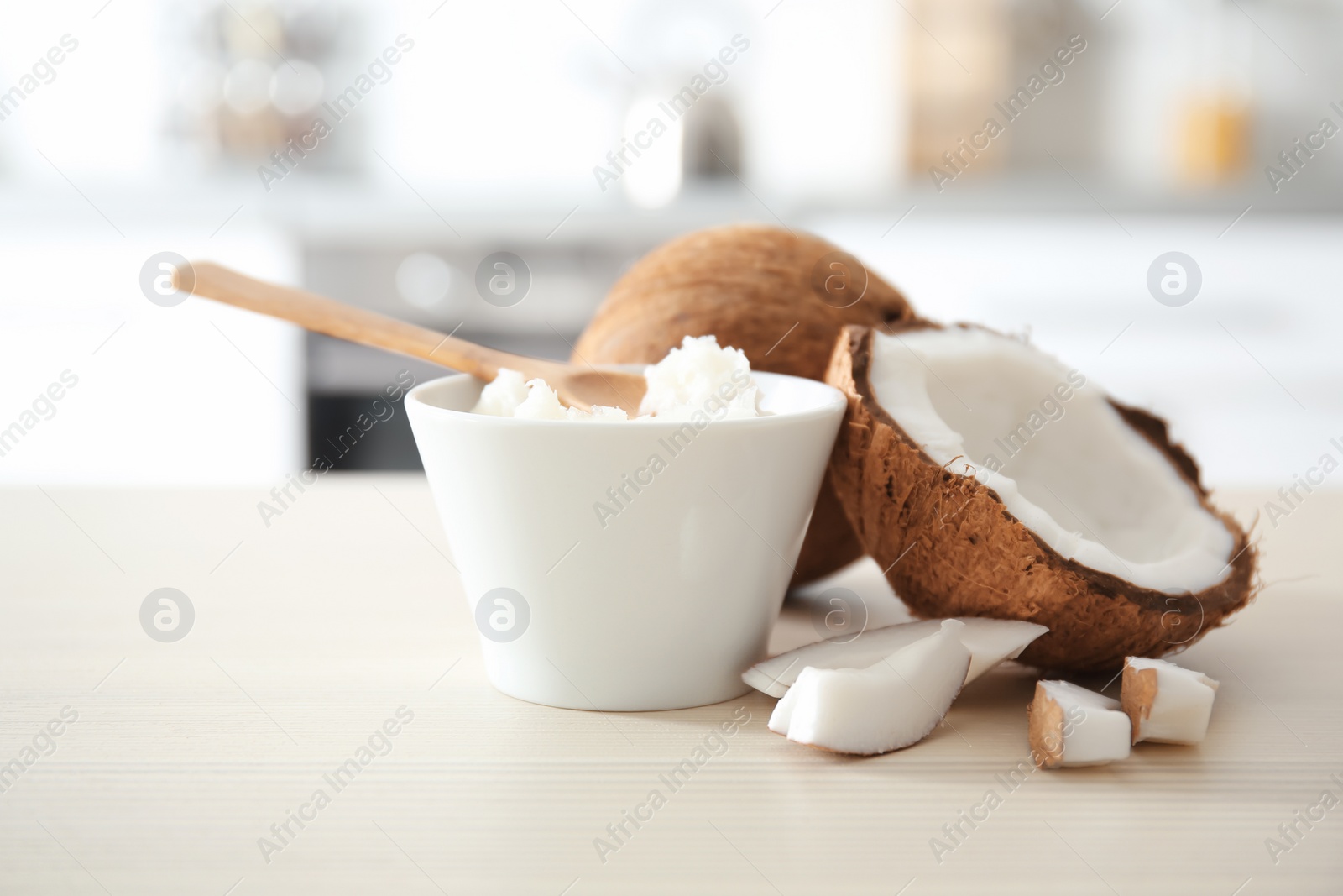 Photo of Bowl with coconut oil and nut pieces on wooden table