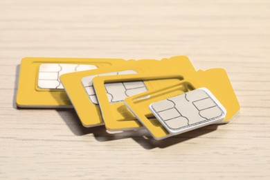 Different SIM cards on wooden background, closeup