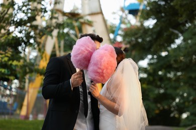 Photo of Newlywed couple with pink cotton candies outdoors
