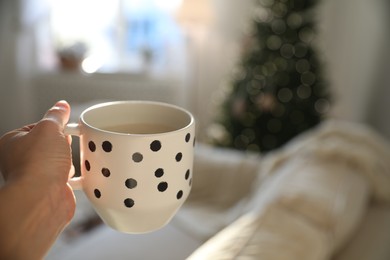 Photo of Woman with cup of cocoa indoors, closeup. Christmas mood