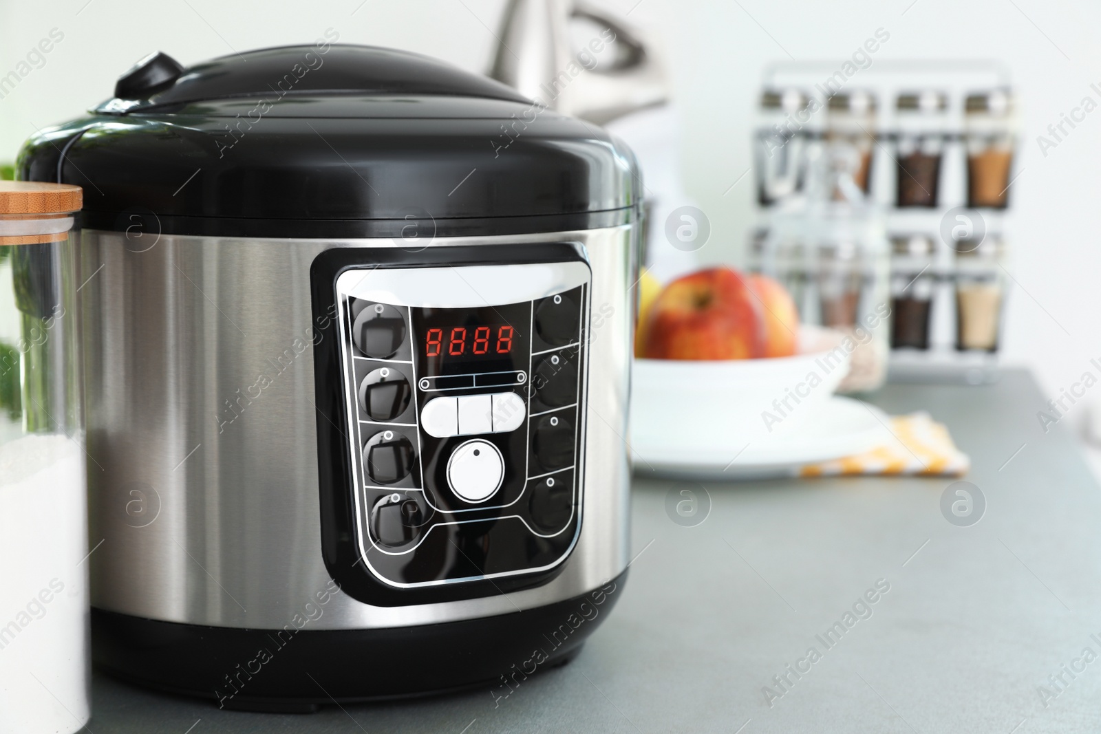 Photo of New modern multi cooker and jar of flour on table in kitchen. Space for text