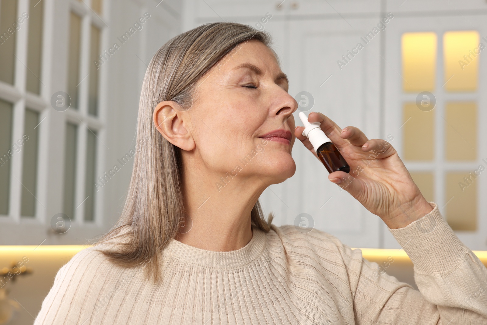 Photo of Medical drops. Woman using nasal spray indoors