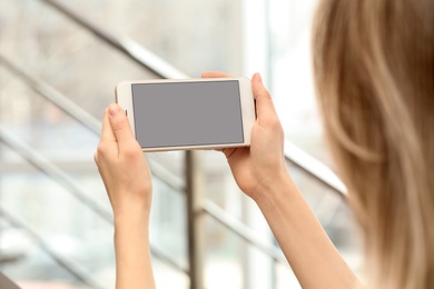 Photo of Young woman using video chat on smartphone indoors, closeup. Space for design