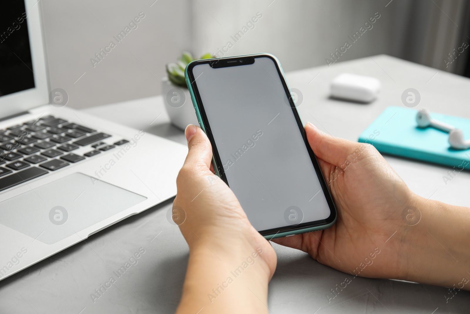 Photo of MYKOLAIV, UKRAINE - JULY 10, 2020: Woman holding Iphone 11 with blank screen at table, closeup. Space for design