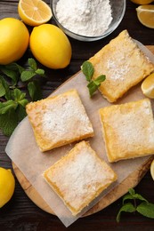 Photo of Tasty lemon bars with powdered sugar and mint on wooden table, flat lay