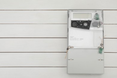 Electric meter on white wooden background, top view with space for text. Measuring device