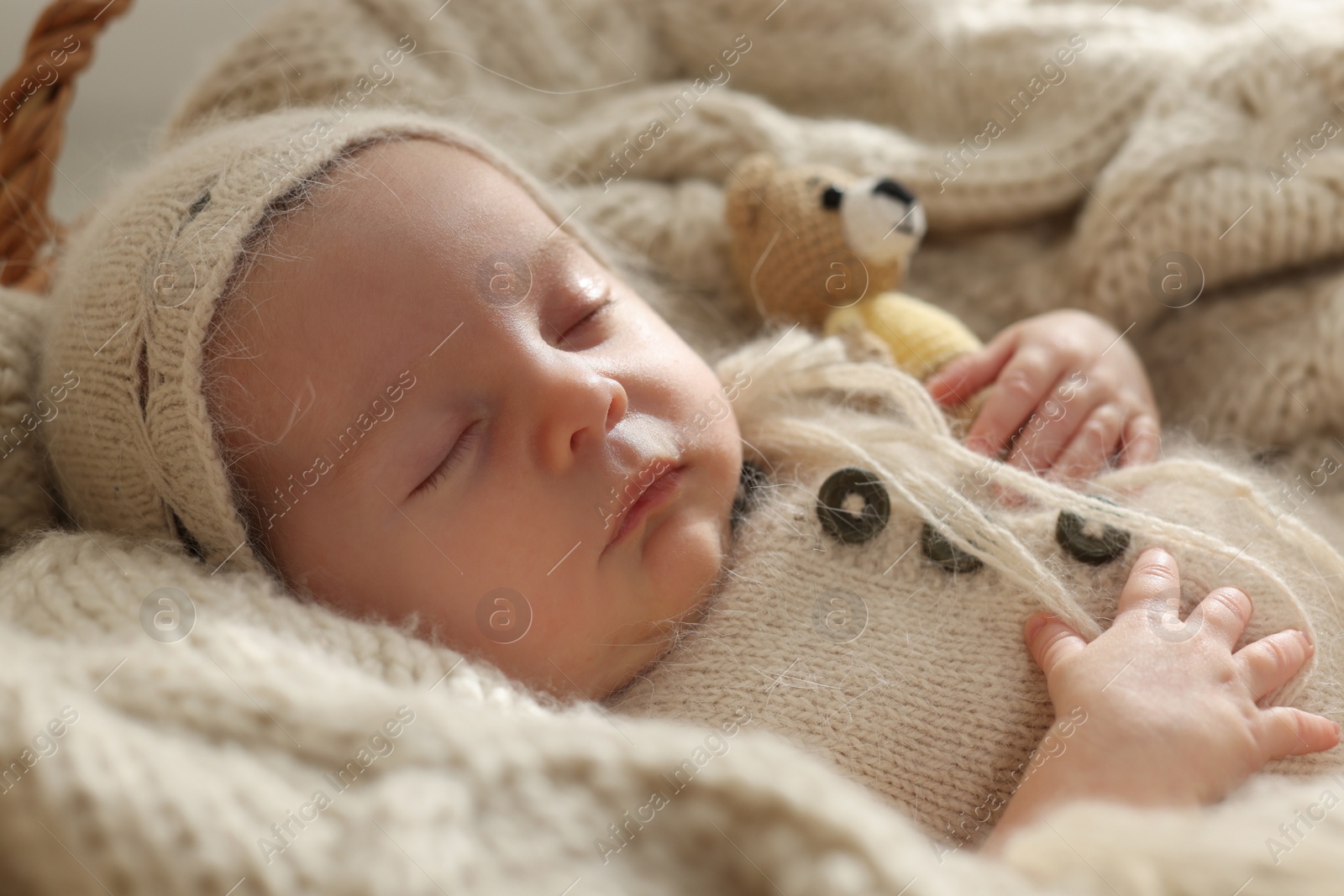 Photo of Adorable newborn baby with toy bear sleeping on knitted plaid, closeup