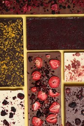 Photo of Different chocolate bars with freeze dried fruits on yellow background, flat lay