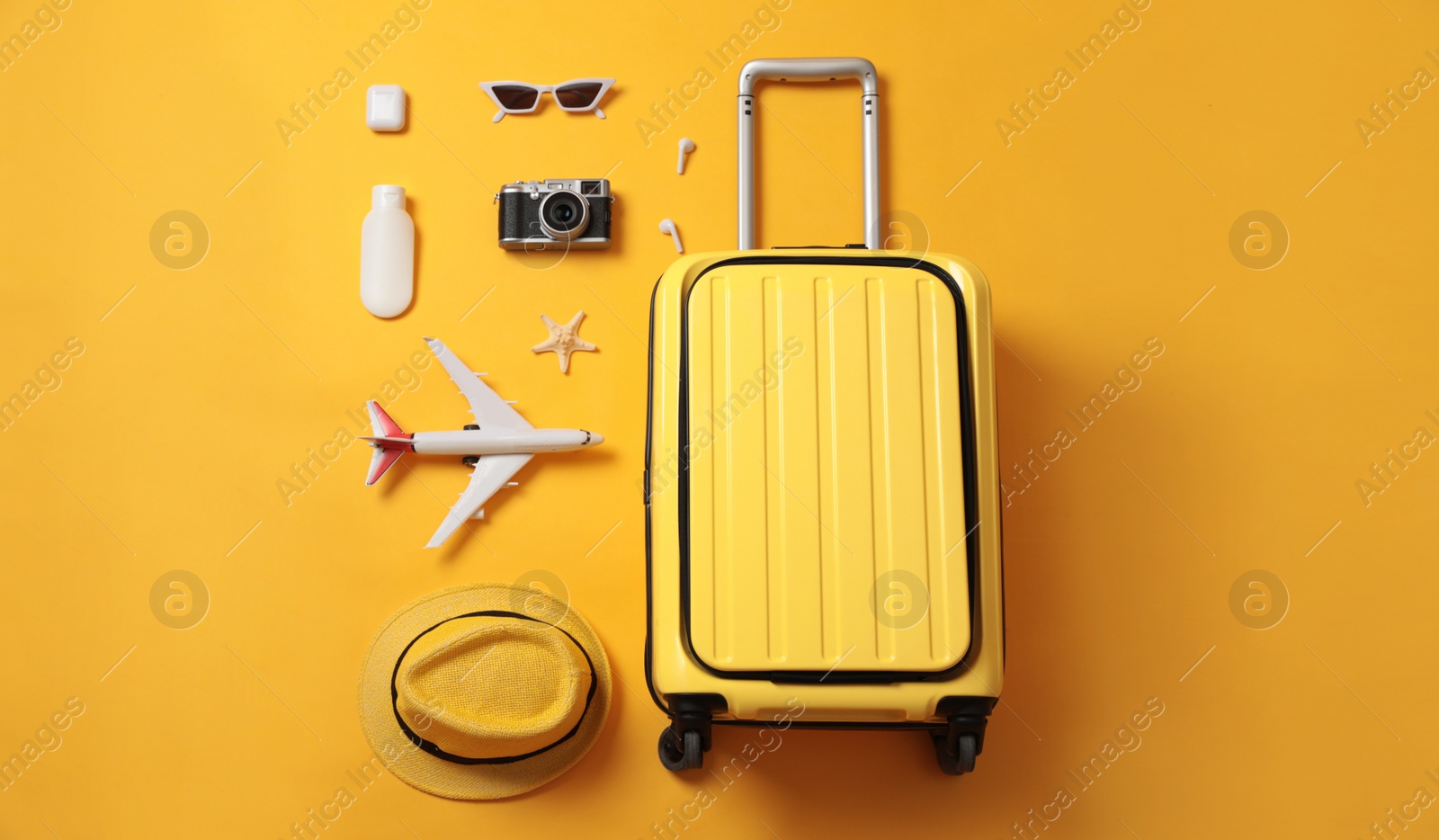 Photo of Flat lay composition with suitcase and travel accessories on yellow background. Summer vacation