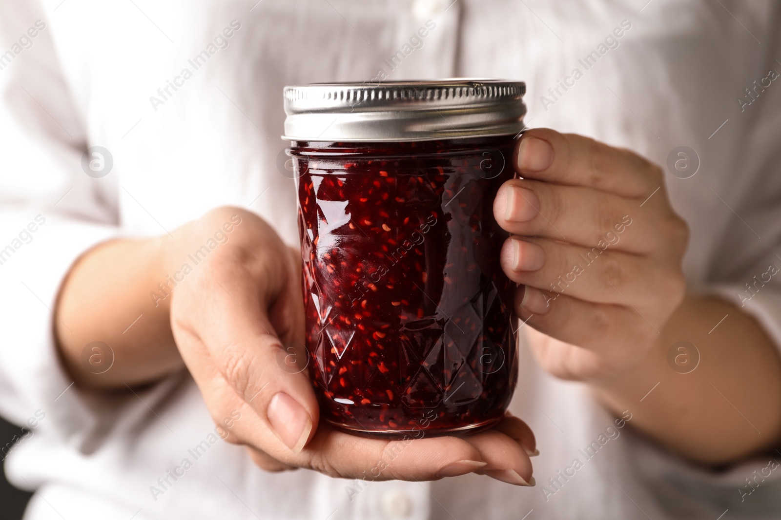 Photo of Woman with jar of raspberry jam, closeup