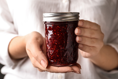 Woman with jar of raspberry jam, closeup