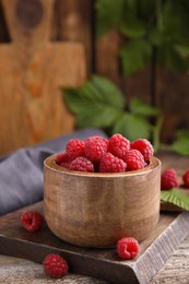 Photo of Bowl of fresh ripe raspberries on wooden table against blurred background