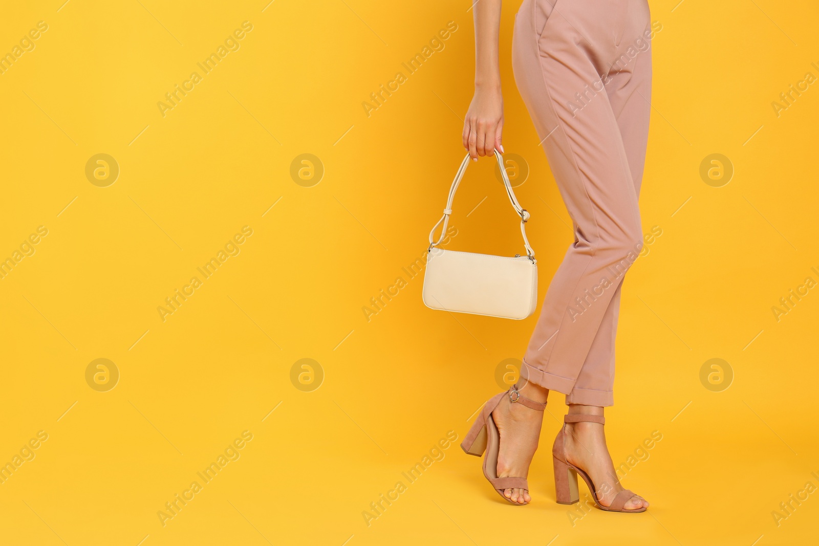 Photo of Woman with stylish bag on yellow background, closeup. Space for text