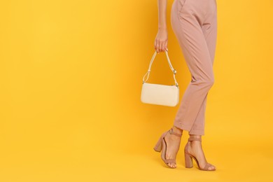 Photo of Woman with stylish bag on yellow background, closeup. Space for text
