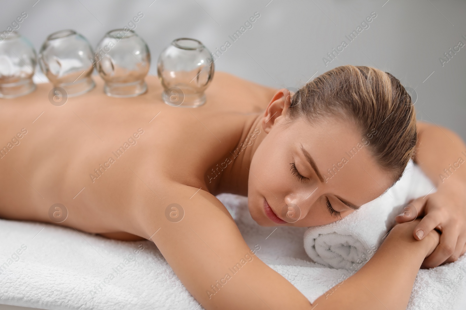 Photo of Cupping therapy. Woman with glass cups on massage couch in spa salon