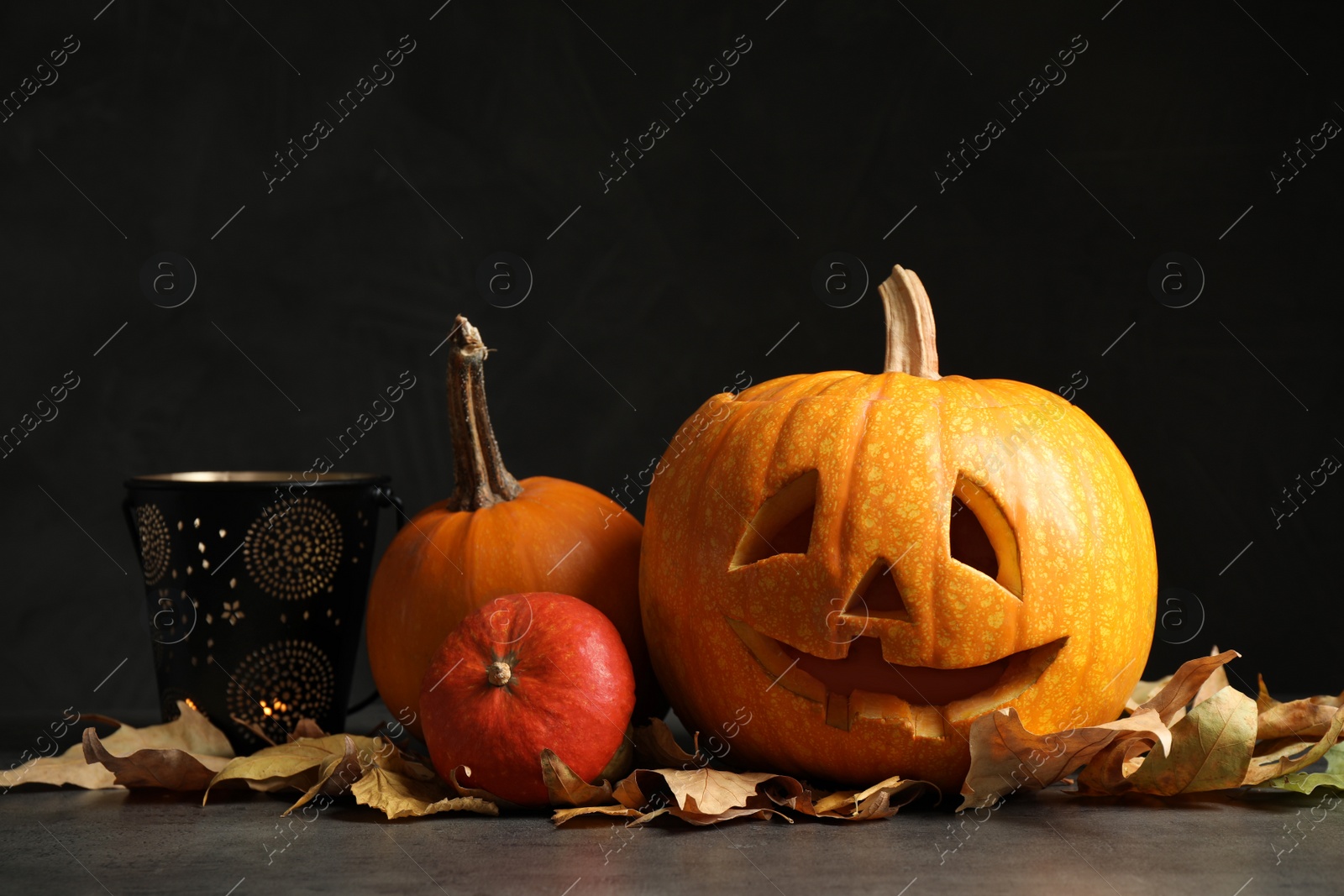 Photo of Composition with pumpkin head on dark background. Jack lantern - traditional Halloween decor