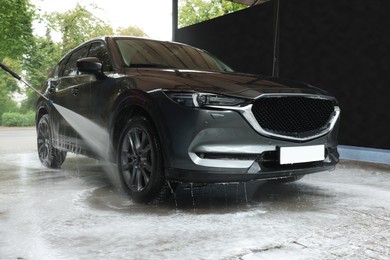 Washing auto with high pressure water jet at outdoor car wash