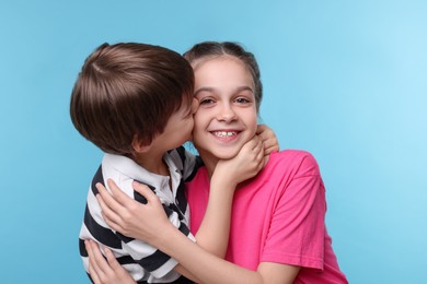 Happy brother and sister on light blue background