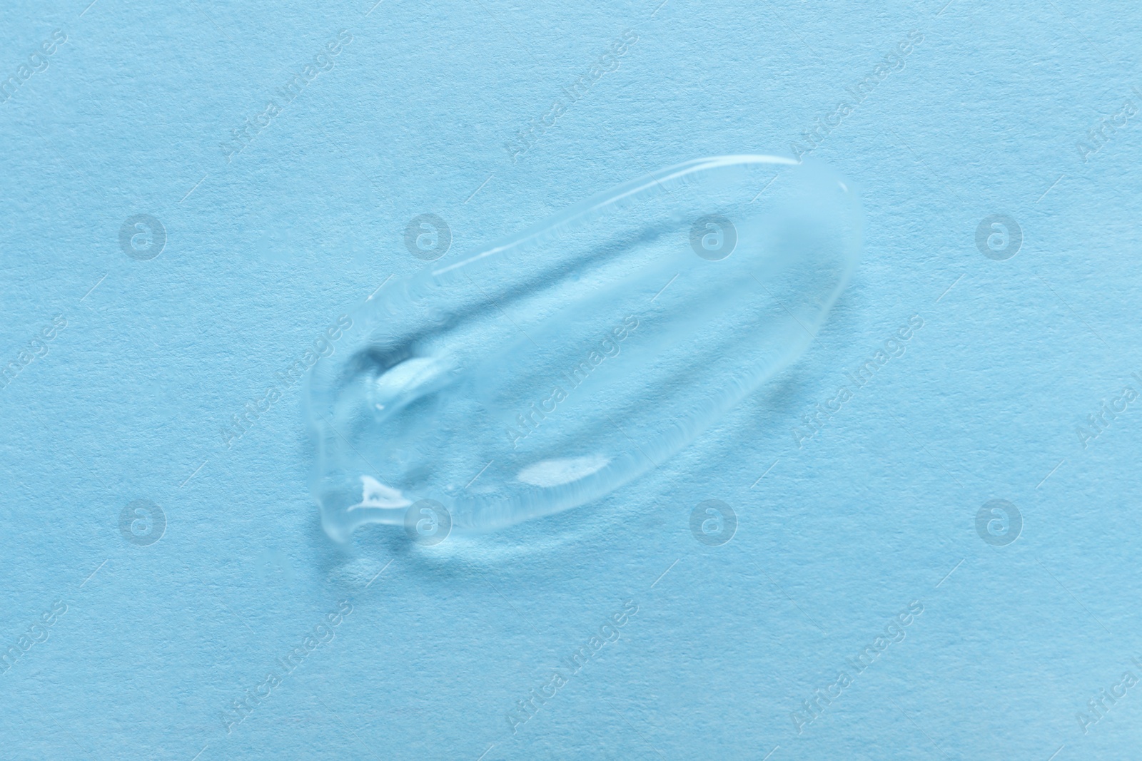 Photo of Sample of transparent gel on light blue background, top view