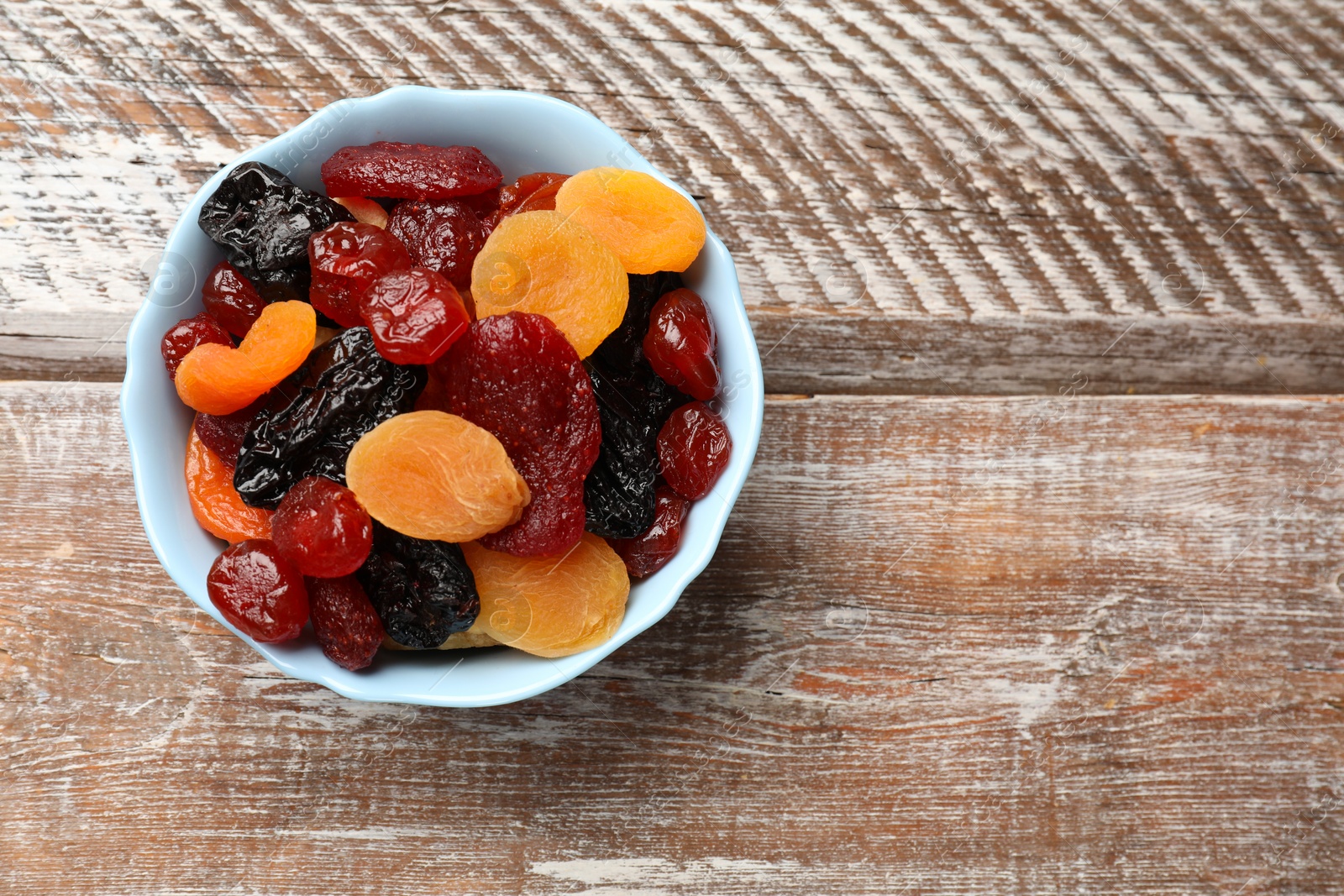 Photo of Mix of delicious dried fruits on wooden table, top view. Space for text