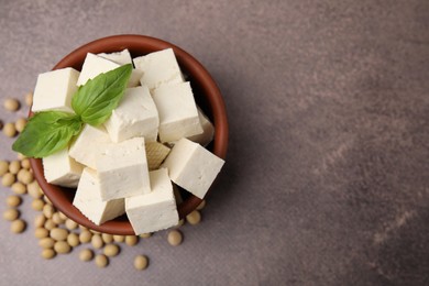 Photo of Delicious tofu cheese, basil and soybeans on brown textured table, flat lay. Space for text
