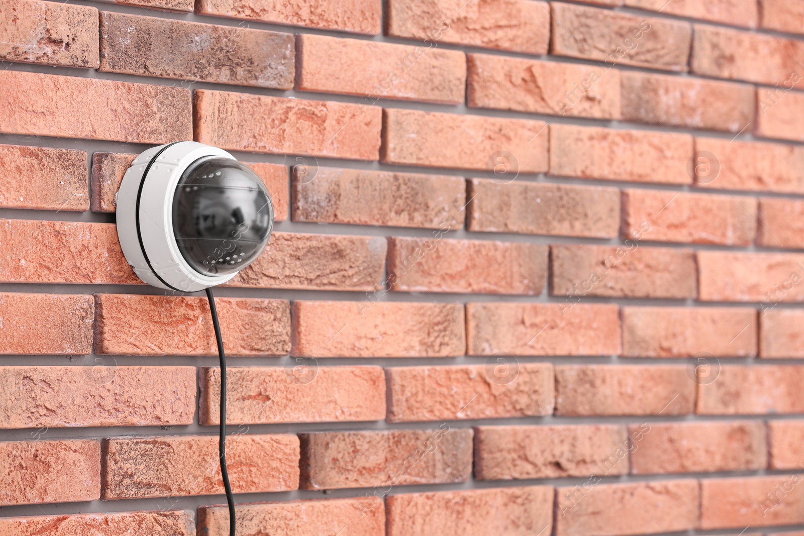 Photo of Modern security CCTV camera on brick wall