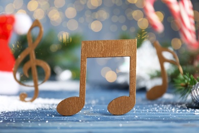 Photo of Wooden music note on light blue table against blurred Christmas lights