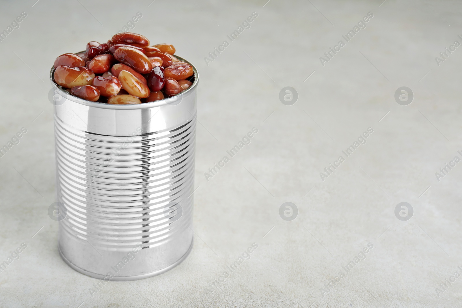 Photo of Tin can with kidney beans on light table, space for text
