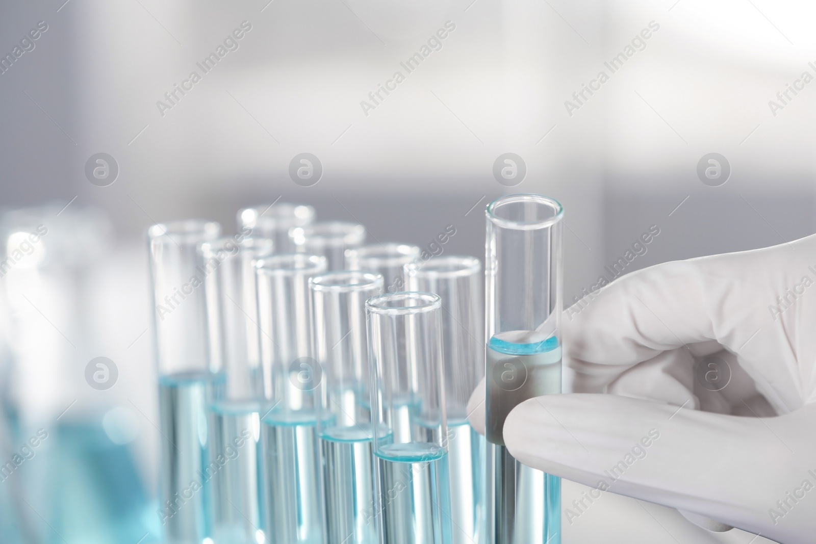 Photo of Analyst holding test tube with fluid in laboratory, closeup. Chemical analysis